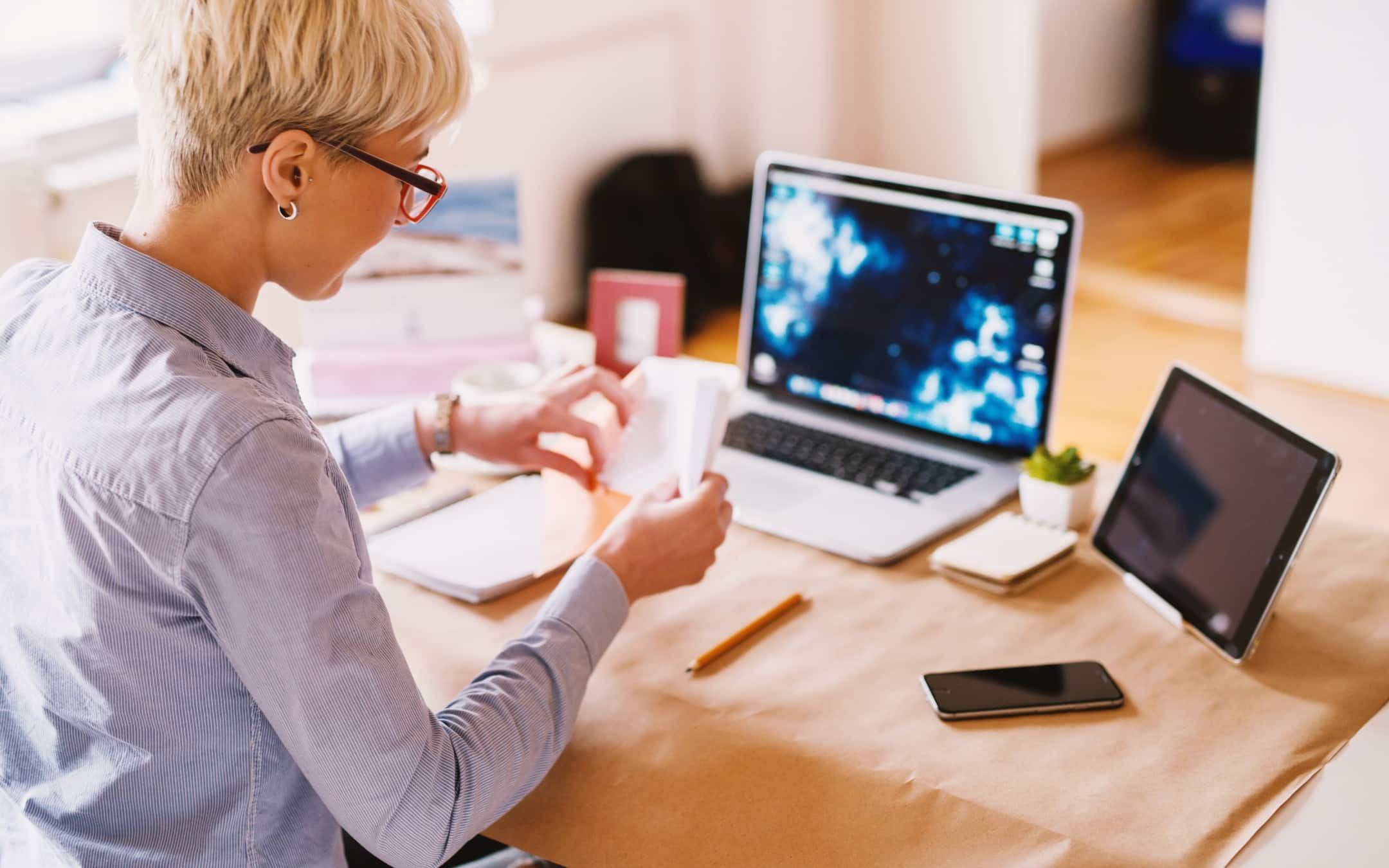 Person arbeitet an einem Schreibtisch mit Laptop, Tablet und Smartphone – symbolisiert digitales Cross-Channel-Marketing.